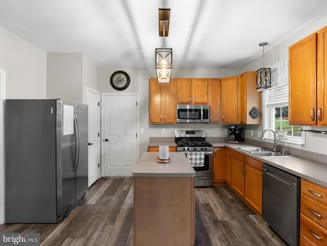 kitchen featuring a kitchen island, dark wood-style flooring, a sink, stainless steel appliances, and decorative light fixtures