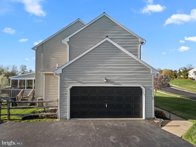 view of home's exterior featuring a sunroom, a garage, and aphalt driveway
