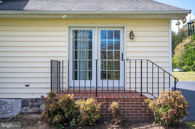 view of exterior entry with roof with shingles