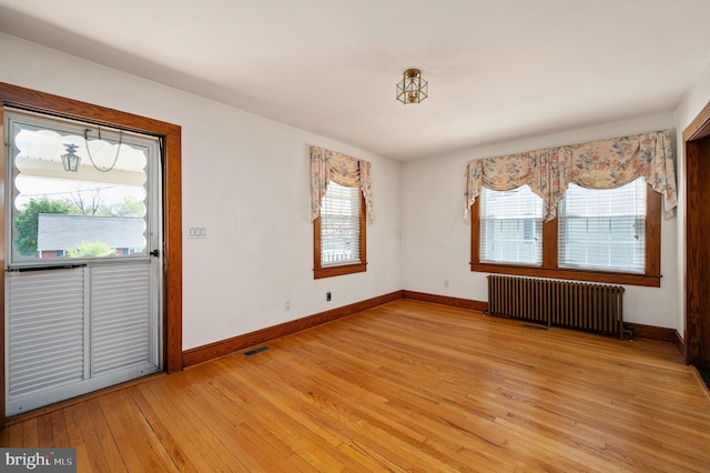 interior space featuring radiator, baseboards, visible vents, and light wood finished floors