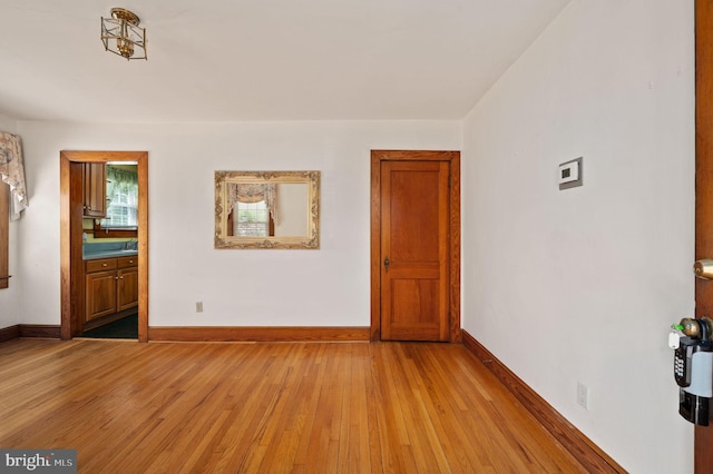 unfurnished room with baseboards and light wood-style floors