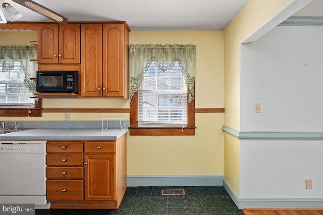kitchen featuring dishwasher, brown cabinetry, black microwave, and light countertops