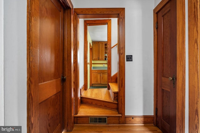 hall with baseboards, wood finished floors, and visible vents