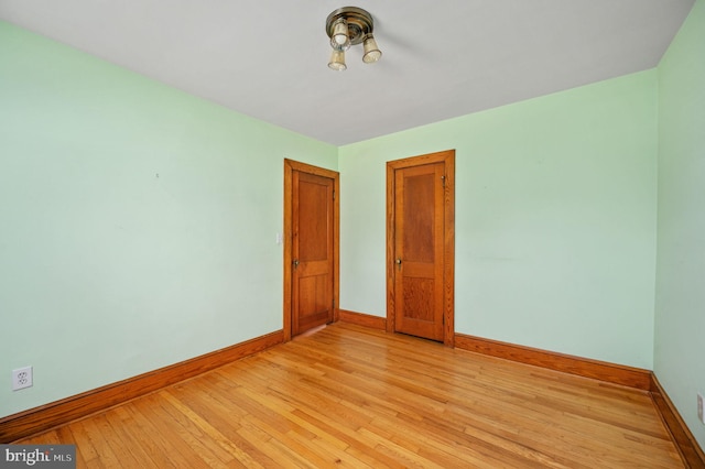 unfurnished room with baseboards and light wood-style flooring