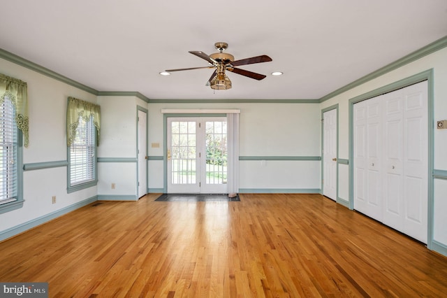 interior space with baseboards, light wood-style floors, ceiling fan, and crown molding