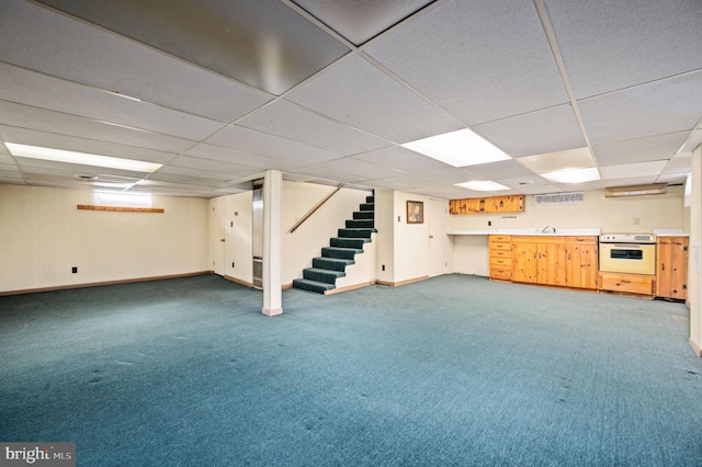 finished below grade area with a drop ceiling, a sink, carpet floors, baseboards, and stairs
