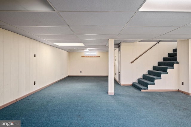 finished basement with baseboards, carpet, stairs, and a paneled ceiling