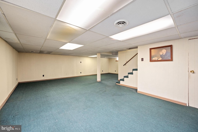 finished below grade area featuring stairway, a drop ceiling, baseboards, carpet flooring, and visible vents