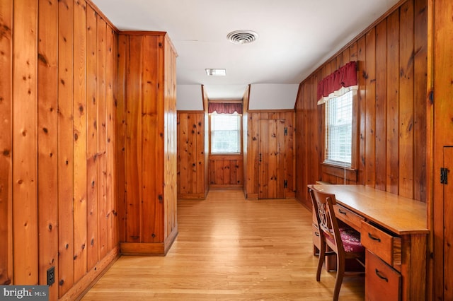 office with wood walls, light wood-style floors, and visible vents