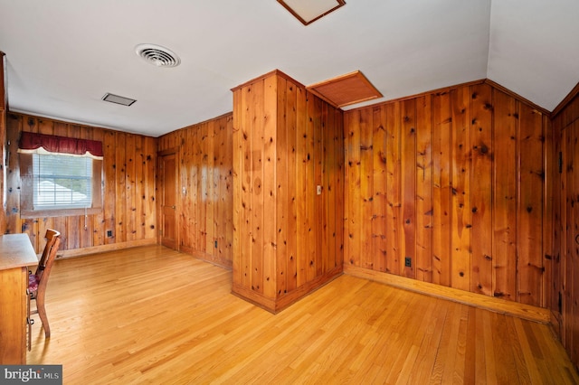bonus room with baseboards, wood walls, visible vents, and light wood-type flooring