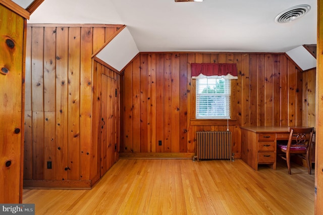 bonus room featuring wooden walls, radiator heating unit, visible vents, and wood finished floors