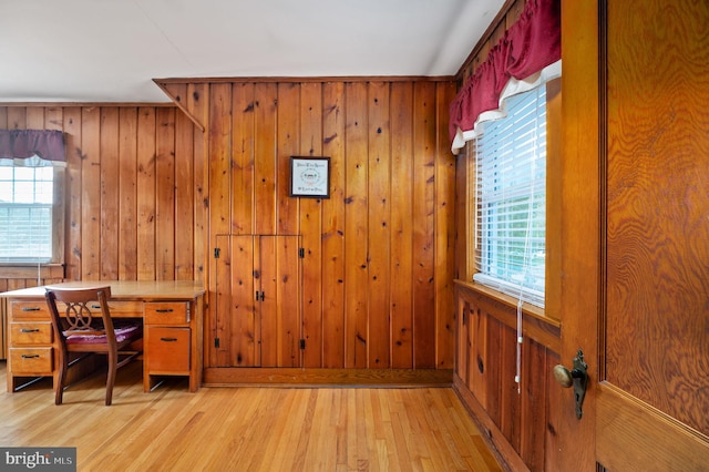 office space with light wood-style floors, a wealth of natural light, and wooden walls