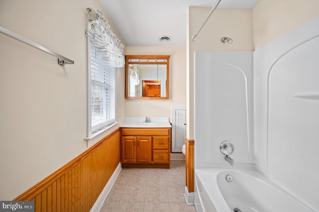 bathroom with tile patterned floors, wainscoting, visible vents, shower / washtub combination, and vanity