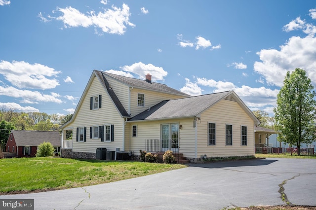 rear view of property with a yard, a chimney, and central AC unit