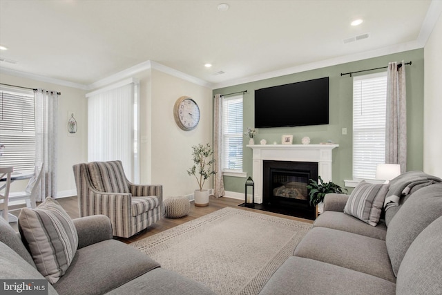 living room featuring ornamental molding, baseboards, wood finished floors, and visible vents