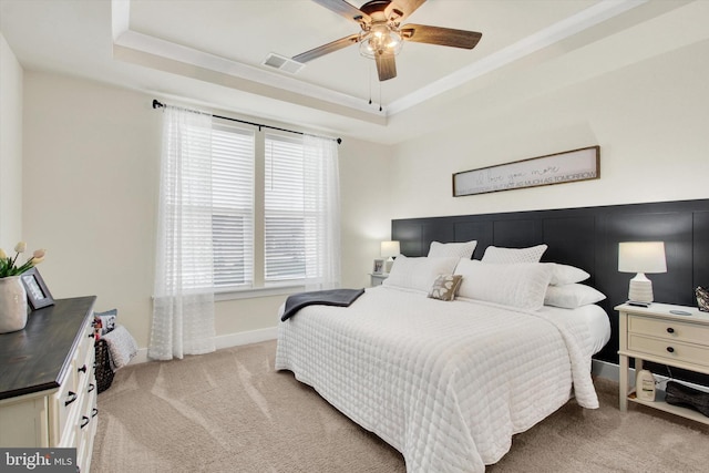 bedroom with a tray ceiling, visible vents, light colored carpet, and baseboards