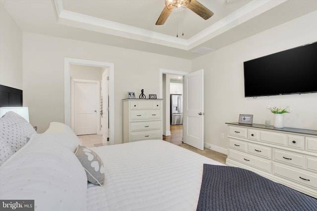bedroom with a tray ceiling, stainless steel fridge with ice dispenser, and baseboards