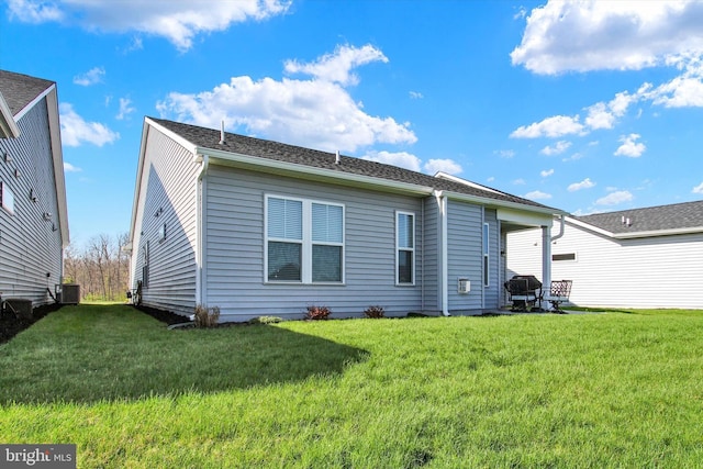 rear view of property with a yard and central AC