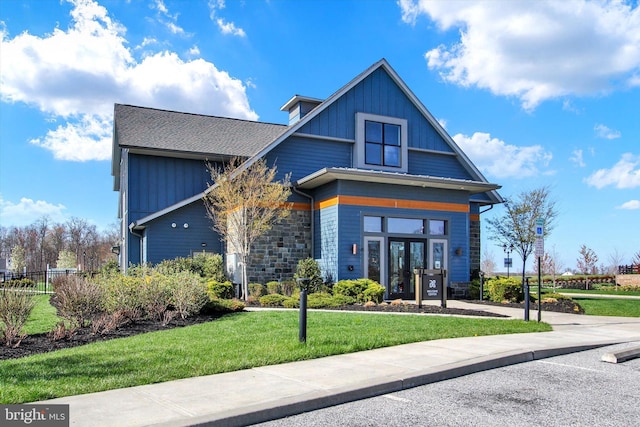 view of front of house featuring a front yard, french doors, stone siding, and fence