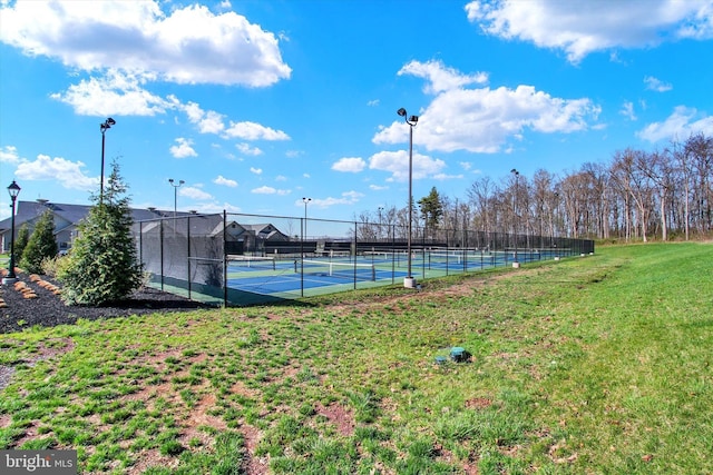 view of swimming pool with a tennis court, a yard, and fence