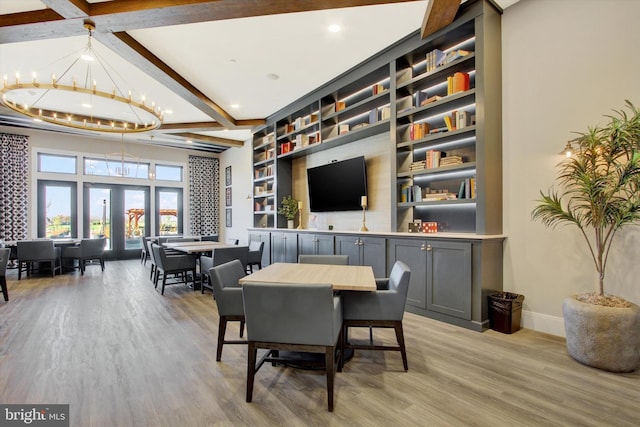 dining space with light wood-type flooring, beamed ceiling, a notable chandelier, and baseboards