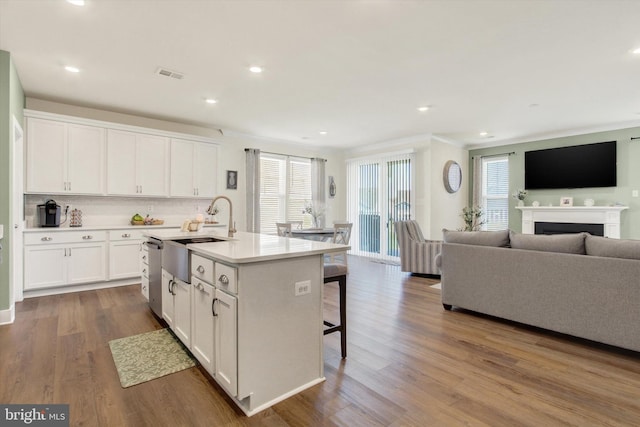 kitchen with visible vents, a sink, open floor plan, white cabinetry, and wood finished floors