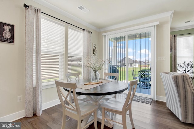 dining space with a healthy amount of sunlight, visible vents, crown molding, and wood finished floors