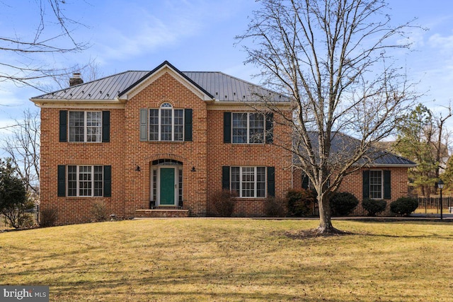 view of front of house with a standing seam roof, a front yard, metal roof, and brick siding