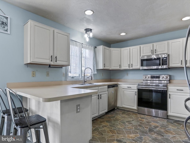 kitchen with a kitchen bar, a peninsula, appliances with stainless steel finishes, and white cabinetry