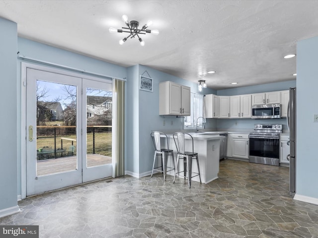 kitchen with a peninsula, a healthy amount of sunlight, white cabinetry, and stainless steel appliances