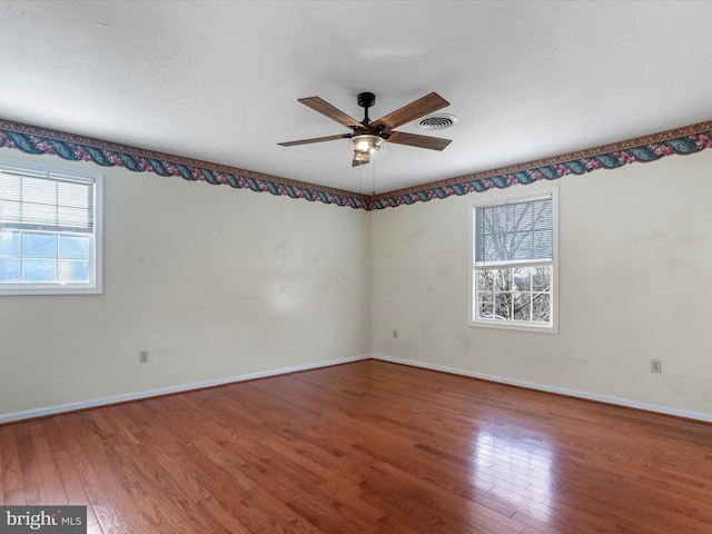 spare room with hardwood / wood-style floors, ceiling fan, baseboards, and visible vents