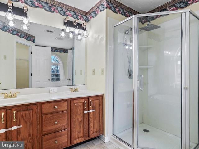 bathroom featuring a shower stall, double vanity, a sink, and visible vents