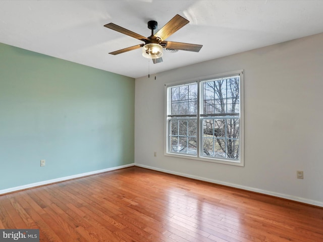 spare room featuring baseboards, hardwood / wood-style floors, and a ceiling fan
