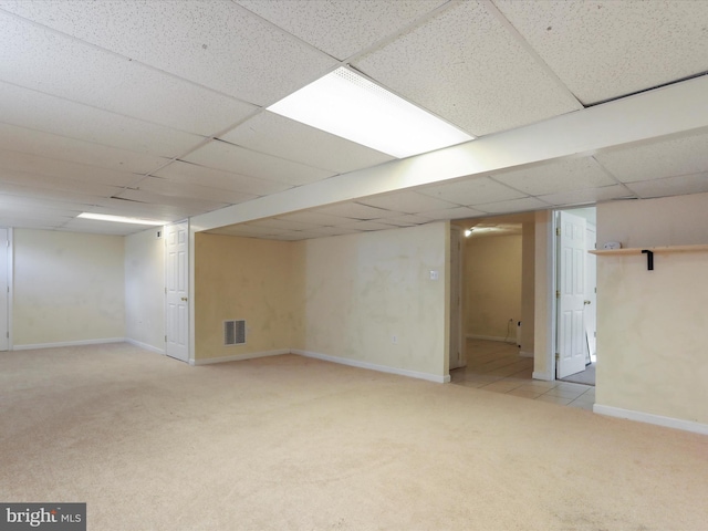 finished below grade area with visible vents, baseboards, a paneled ceiling, and carpet