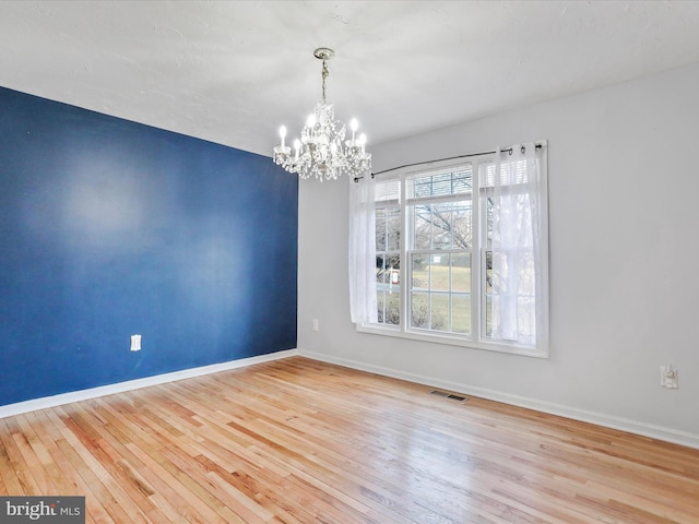 unfurnished room featuring a chandelier, baseboards, wood-type flooring, and visible vents