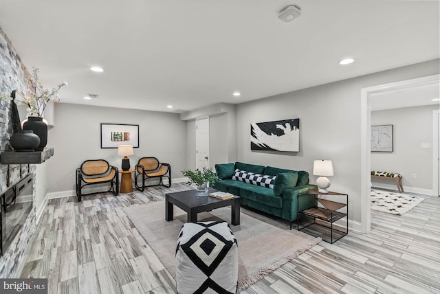 living room with light wood-type flooring, recessed lighting, baseboards, and a fireplace