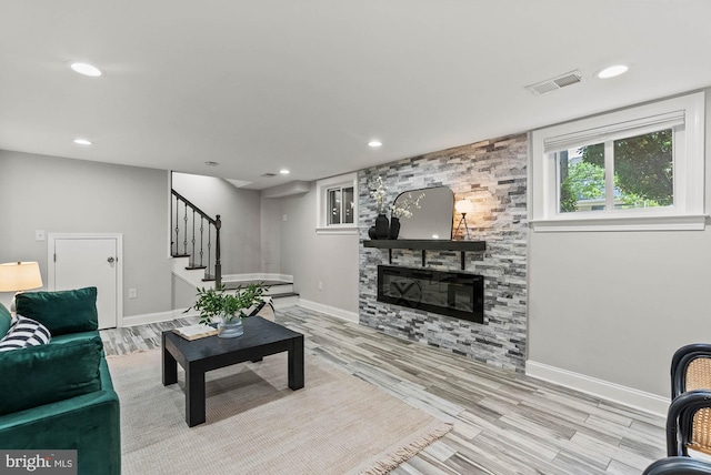 living room with visible vents, baseboards, wood finished floors, and stairway