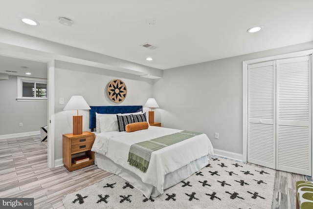 bedroom with baseboards, light wood finished floors, and visible vents