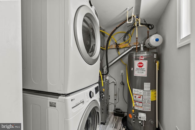 washroom featuring water heater, baseboards, laundry area, and stacked washer / dryer