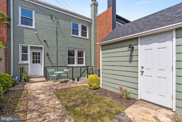 back of property featuring cooling unit and brick siding