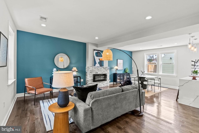 living room featuring visible vents, wood finished floors, a fireplace, baseboards, and recessed lighting