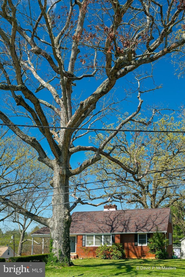 ranch-style home featuring brick siding, a chimney, and a front yard