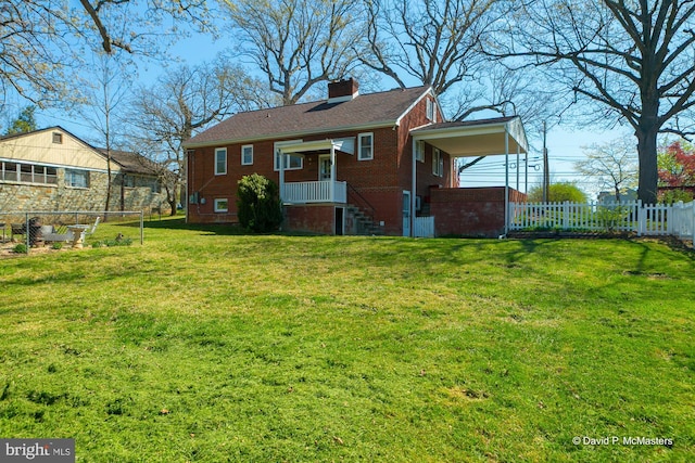 rear view of property featuring a lawn, brick siding, fence, and a chimney