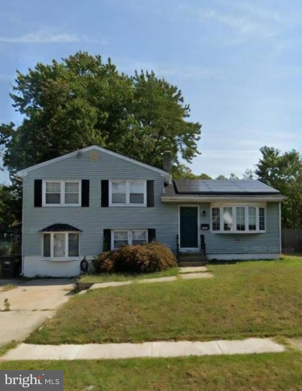 tri-level home with entry steps, a front lawn, and solar panels