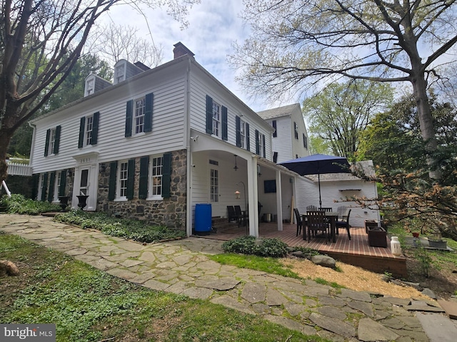 2531 Pickwick Rd, Baltimore, MD 21207 - exterior space with stone siding, a chimney, outdoor dining area, and a deck