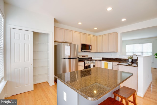 8114 Rainwater Cir, Manassas, VA 20111 - kitchen featuring a sink, stainless steel appliances, light wood finished floors, a kitchen bar, and a peninsula
