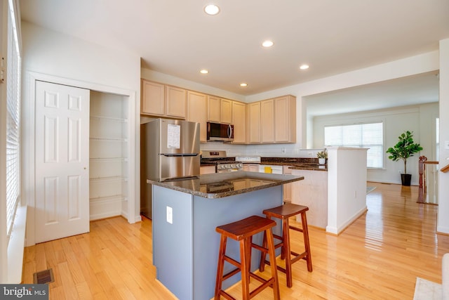 8114 Rainwater Cir, Manassas, VA 20111 - kitchen with stainless steel appliances, light wood-style flooring, light brown cabinetry, visible vents, and a breakfast bar area