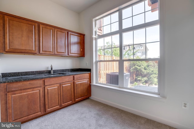 8114 Rainwater Cir, Manassas, VA 20111 - kitchen with brown cabinetry, dark stone counters, a sink, and light colored carpet
