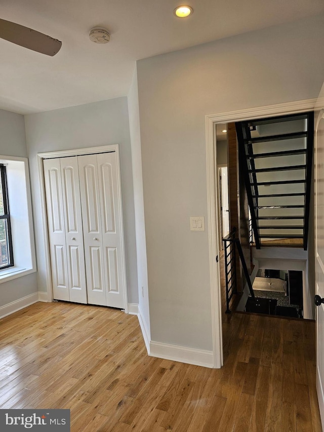 unfurnished bedroom featuring a closet, recessed lighting, wood-type flooring, and baseboards