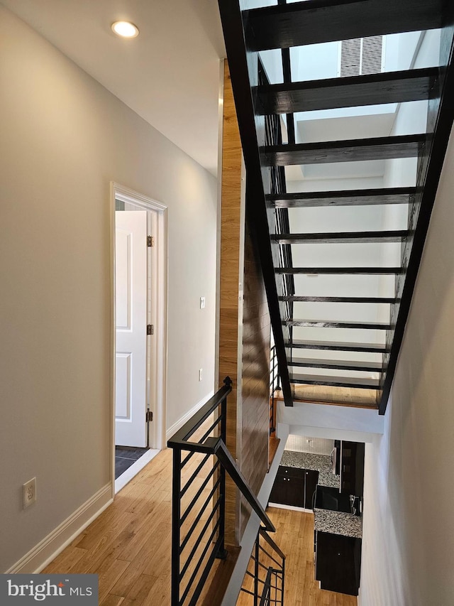 stairway with recessed lighting, baseboards, and wood finished floors